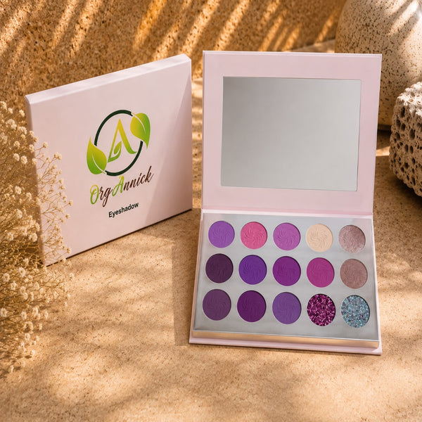 An open OrgAnnick Eyeshadow palette with 15 circular pans in shades of purple, pink, beige, and glitter