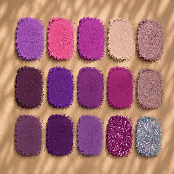 Twelve square textured swatches arranged in a 3-by-4 grid on a beige surface with soft shadow overlays. The swatches range from lavender and purple to hot pink, lilac, glittery magenta, and a pale icy blue.